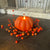 Decorative pumpkin candle with berries on a dark surface
